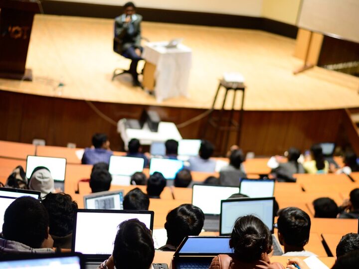 A lecture hall mid-session, students working on laptops
